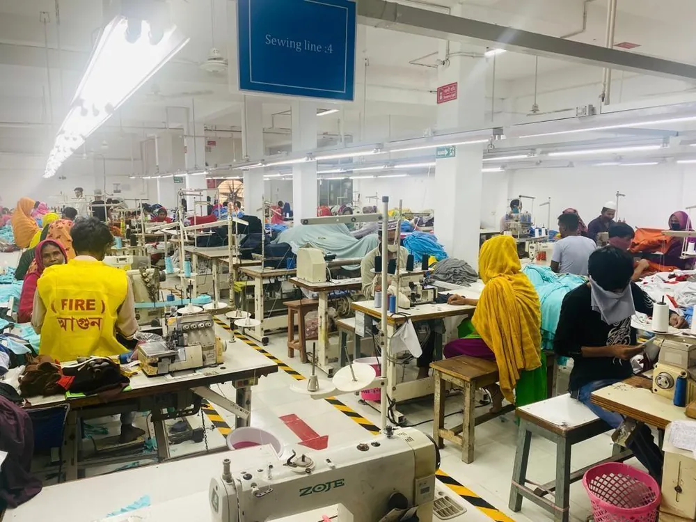 Long view of a busy sewing floor with rows of operators